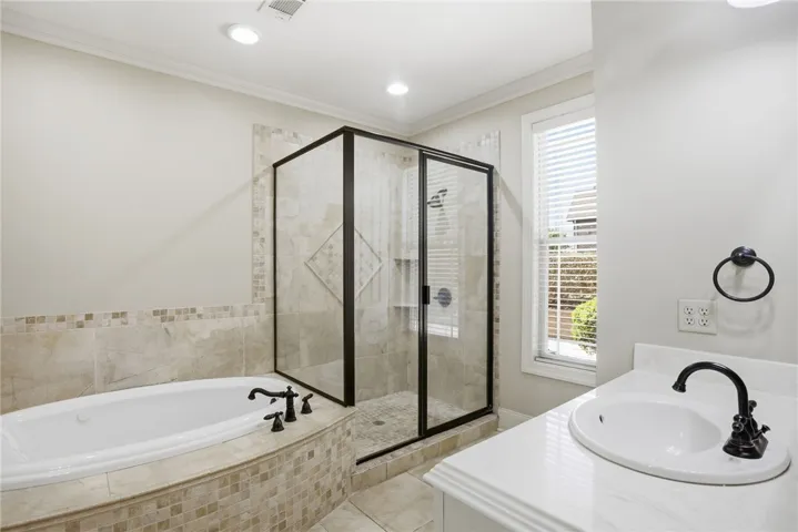 This serene bath offers a spacious soaking tub and a sleek glass-enclosed shower.
