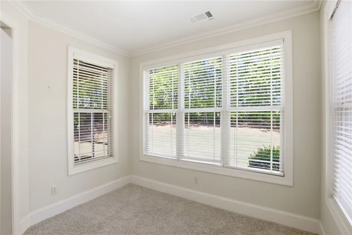 This bright room features abundant natural light and soft carpeting, creating a welcoming atmosphere.