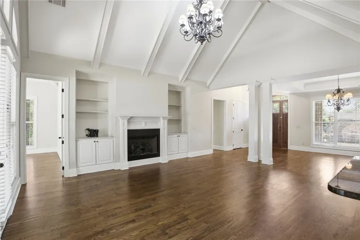 This expansive living area features a fireplace and gleaming hardwood floors under vaulted ceilings.