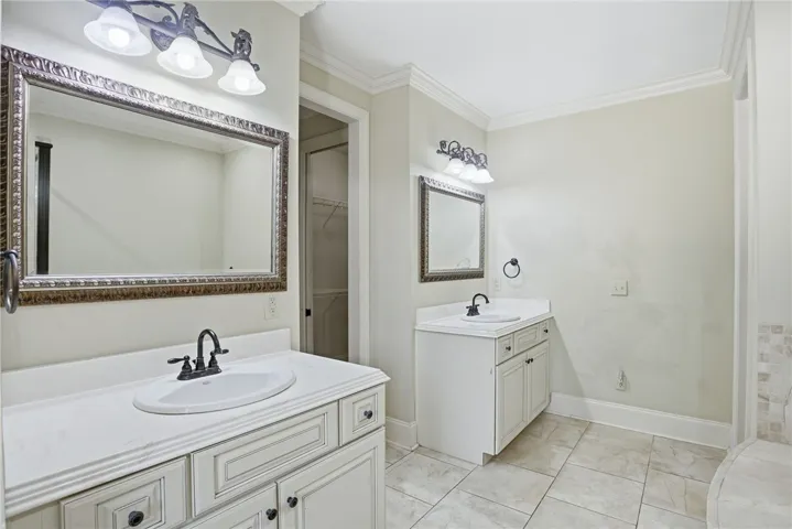 This bright bathroom features dual vanities and elegant tile flooring.