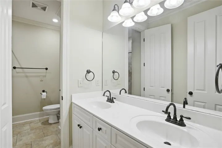 This bathroom features dual sinks with ample counter space and a private commode area.