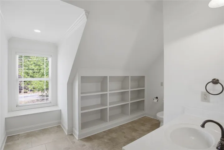 This bright bathroom features a spacious built-in shelving unit, offering practical storage solutions.
