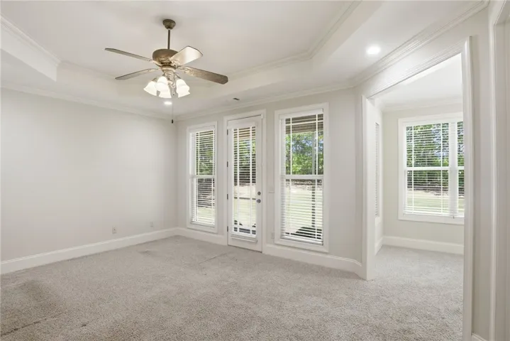 This spacious room features abundant natural light, plush carpeting, and elegant crown molding.