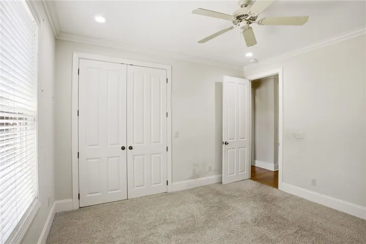 This spacious bedroom offers comfortable carpeting and elegant crown molding, perfect for serene living.