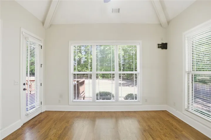 This airy bonus room features abundant natural light, exposed ceiling beams, and polished wood floors.