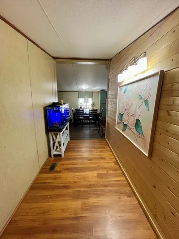This inviting hallway features warm wood flooring leading to a bright dining area.