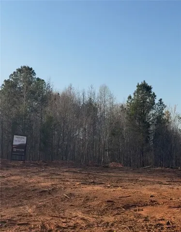 This expansive lot, cleared and ready for development, offers a serene setting bordered by mature trees.