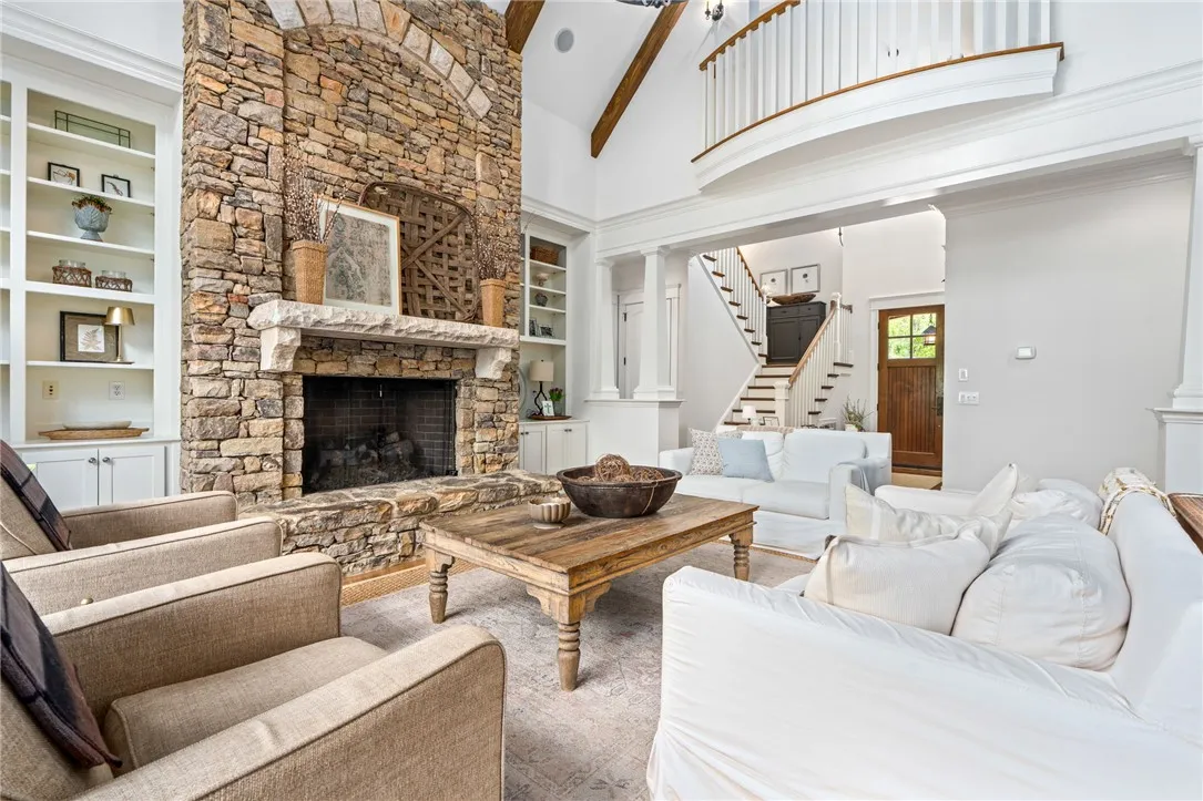 A vaulted ceiling with wood beams and stone fireplace steals the spotlight in this breathtaking living room.