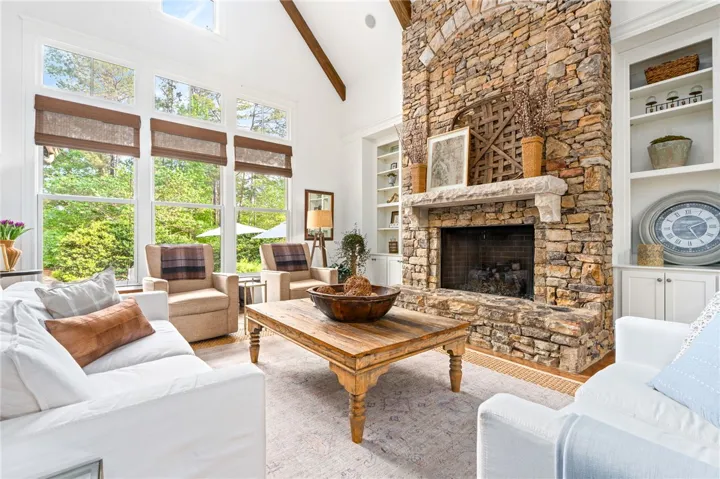 A vaulted ceiling with wood beams and stone fireplace steals the spotlight in this breathtaking living room.