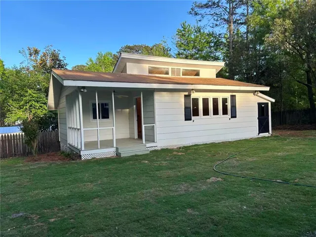 This charming residence features a well-maintained exterior with a inviting porch and lush green surroundings.