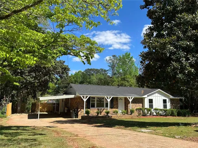 This charming residence features a classic brick and wood exterior under a bright sky.