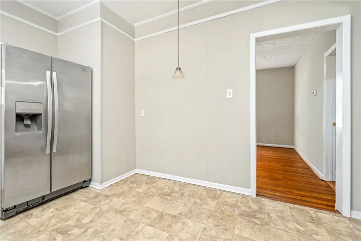 This bright kitchen features a large refrigerator and practical tiled flooring, perfect for daily living.