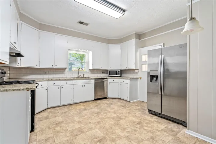 This spacious kitchen offers ample cabinet storage, generous counter space, and durable flooring for daily living.