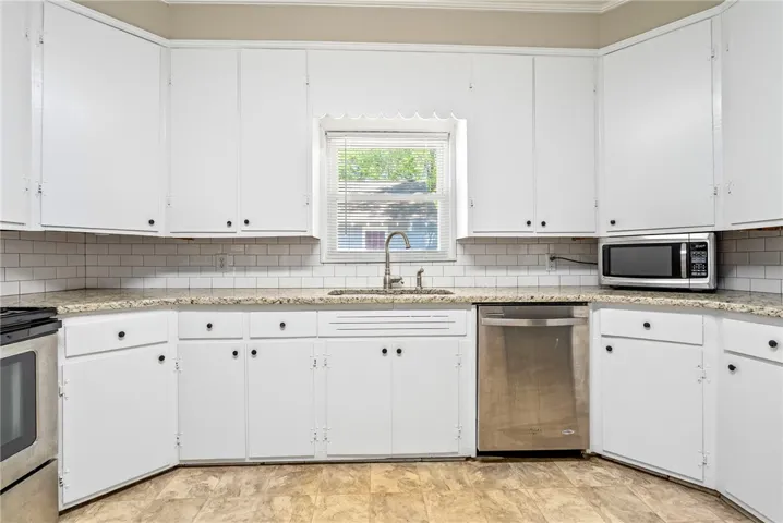 This bright kitchen features white cabinetry and modern appliances, creating a pristine and functional culinary space.