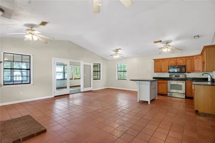 This expansive space integrates living and cooking with warm tiled flooring and vaulted ceilings.
