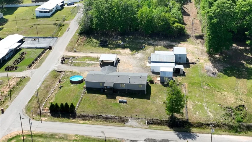 This elevated view captures a sprawling property with a welcoming pool and functional outbuildings.