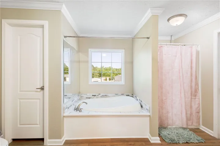 This serene bathroom offers a soaking tub with an exterior view and a separate shower.