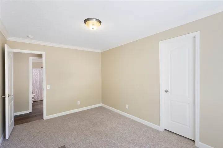 This inviting bedroom features soft carpet and crown molding, with an adjacent bathroom for convenience.