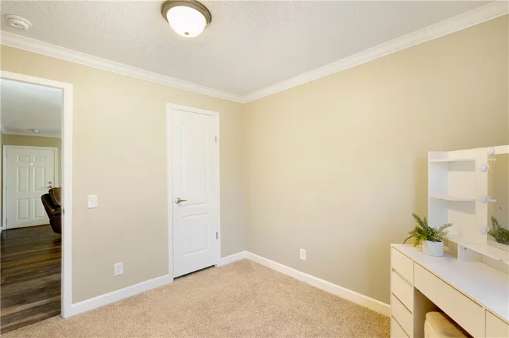 This cozy bedroom features plush carpeting and elegant crown molding, creating a comfortable living space.