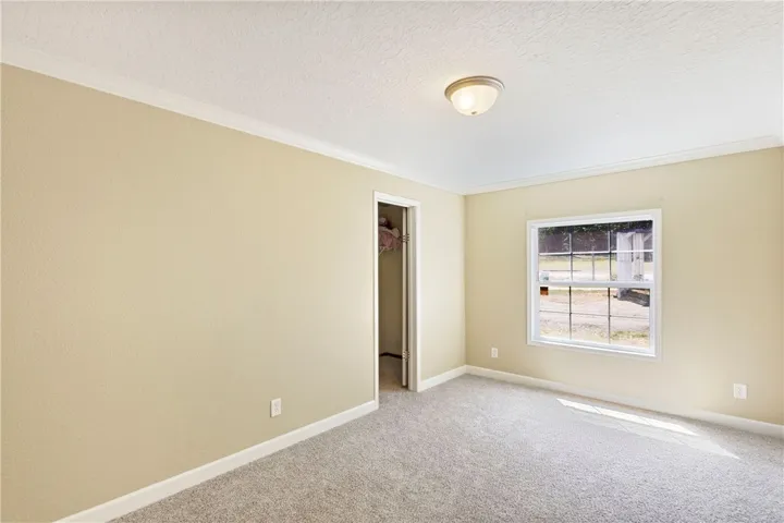 This inviting bedroom features soft carpeting and a window overlooking the verdant outdoors.