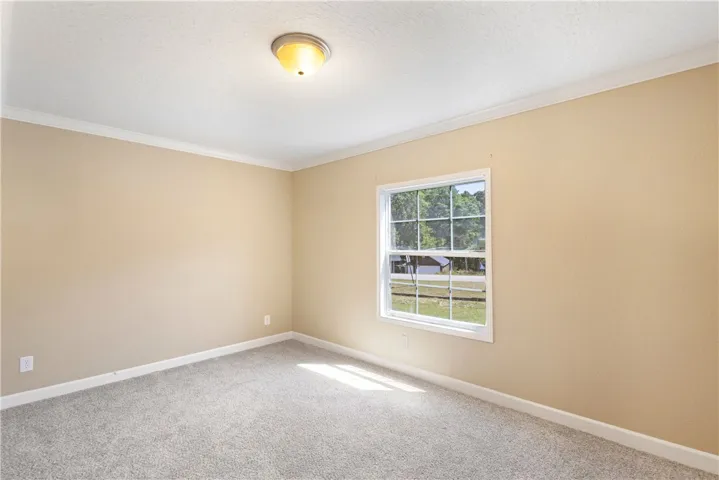 This spacious room features a large window offering views of the outdoors and cozy carpeting.