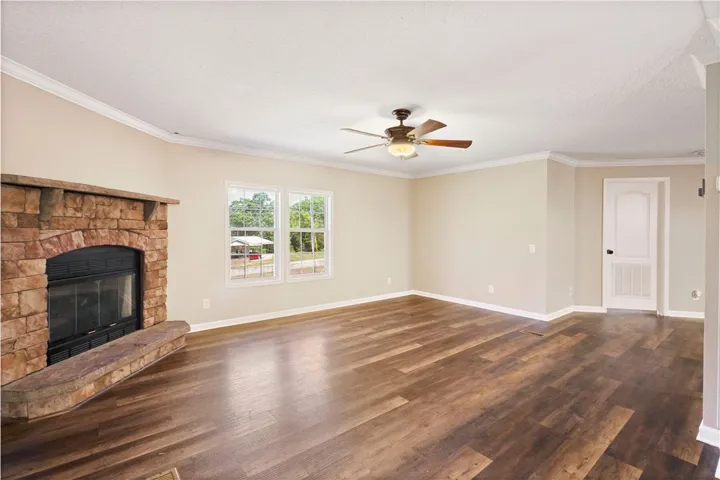 This bright living space features rich flooring, a cozy fireplace, and crown molding.