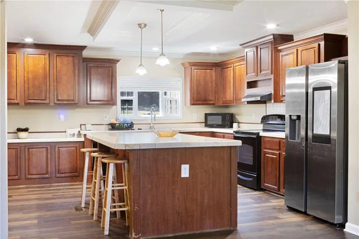 This kitchen features rich cabinetry, practical appliances, and a central island with bar seating.
