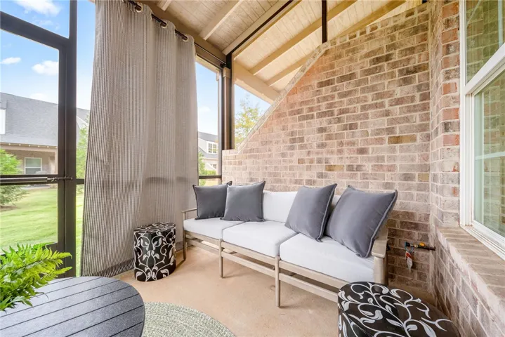 This inviting covered patio features a beautiful brick accent wall and ample space for outdoor relaxation.