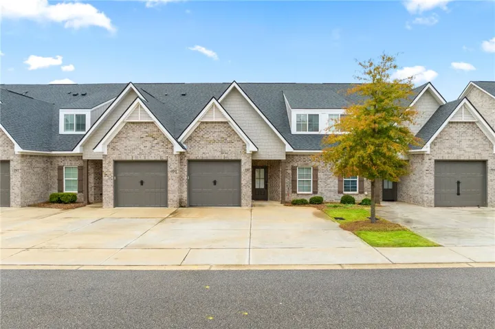 This charming brick exterior features dormer windows and attached garages, creating a welcoming and functional home.