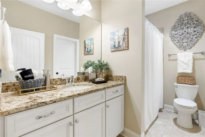 This bathroom features a granite countertop, white vanity, and tile flooring, offering a fresh design.