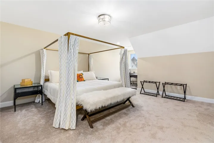 This spacious bedroom offers comfortable carpeting and sloped ceilings, perfect for a cozy retreat.