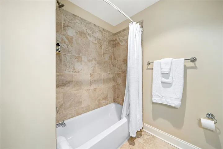 This bathroom features a shower and tub combination with elegant tile work and practical fixtures.