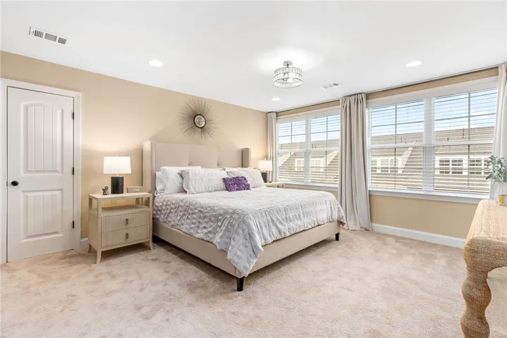 This primary bedroom features plush carpeting and abundant natural light through multiple windows.