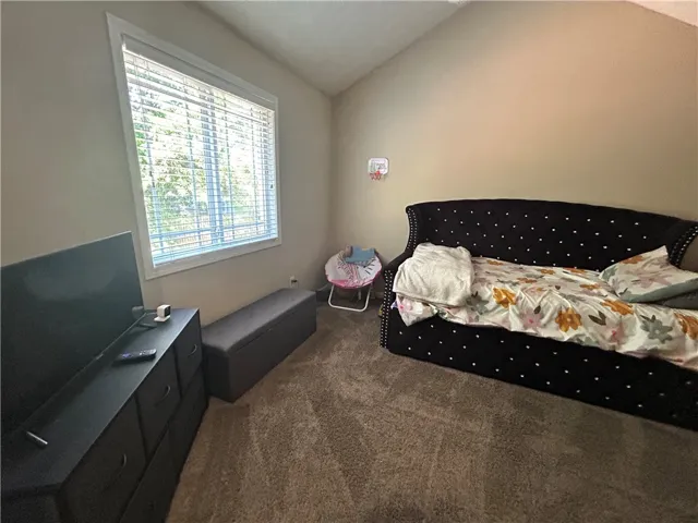 This cozy bedroom offers a serene retreat with soft carpeting and natural light filtering through the window.