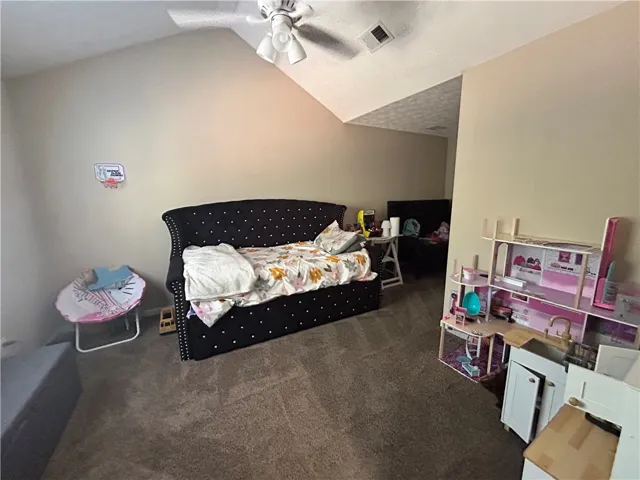 This spacious bedroom features vaulted ceilings and soft carpeting, creating a comfortable and inviting atmosphere.