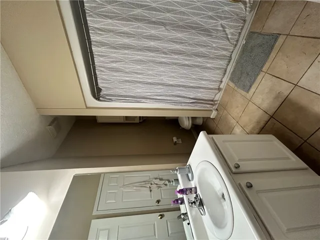 This bathroom features a simple vanity, tiled flooring, and a tub/shower combo.