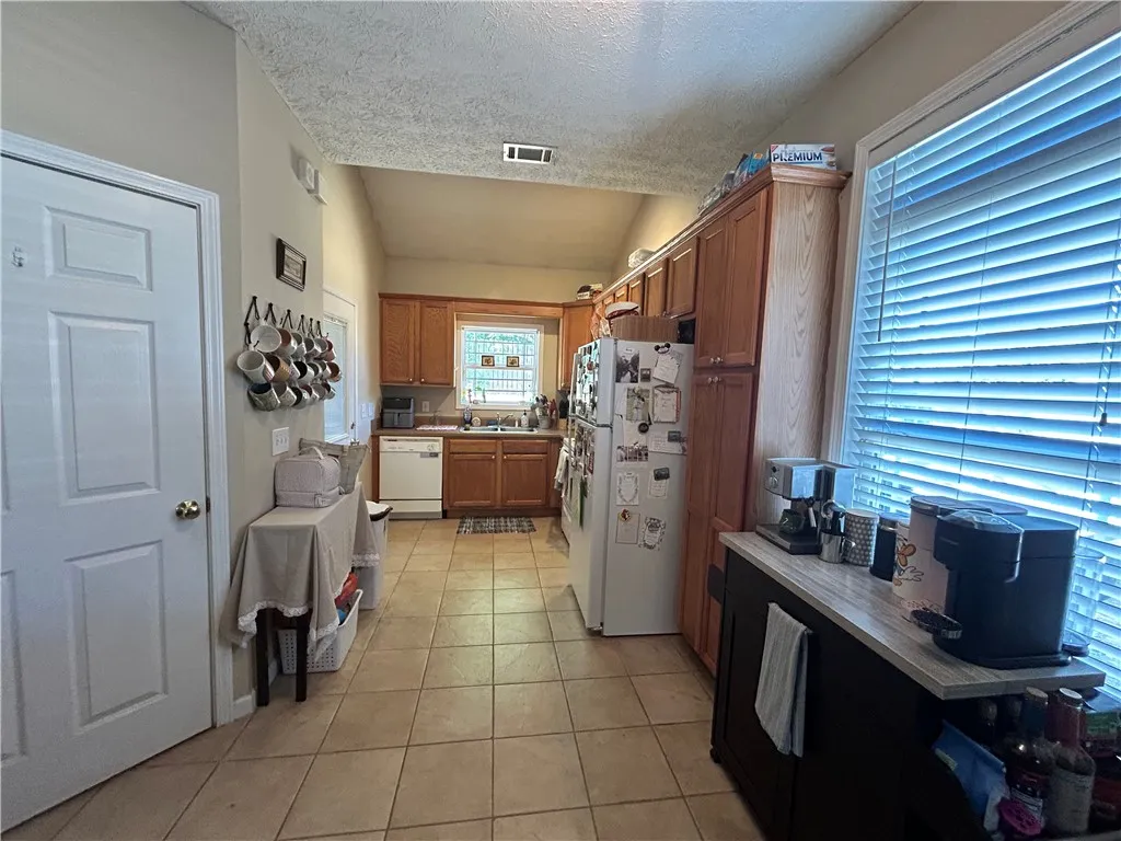 This kitchen features classic cabinetry, practical tile flooring, and ample natural light.