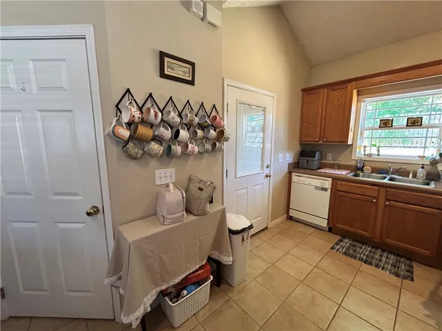 This kitchen features rich wooden cabinetry, tile flooring, and a window overlooking lush greenery.