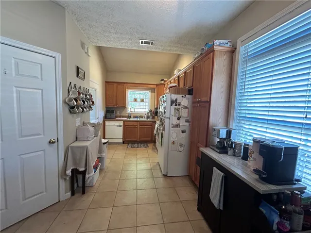 This kitchen features classic cabinetry, practical tile flooring, and ample natural light.