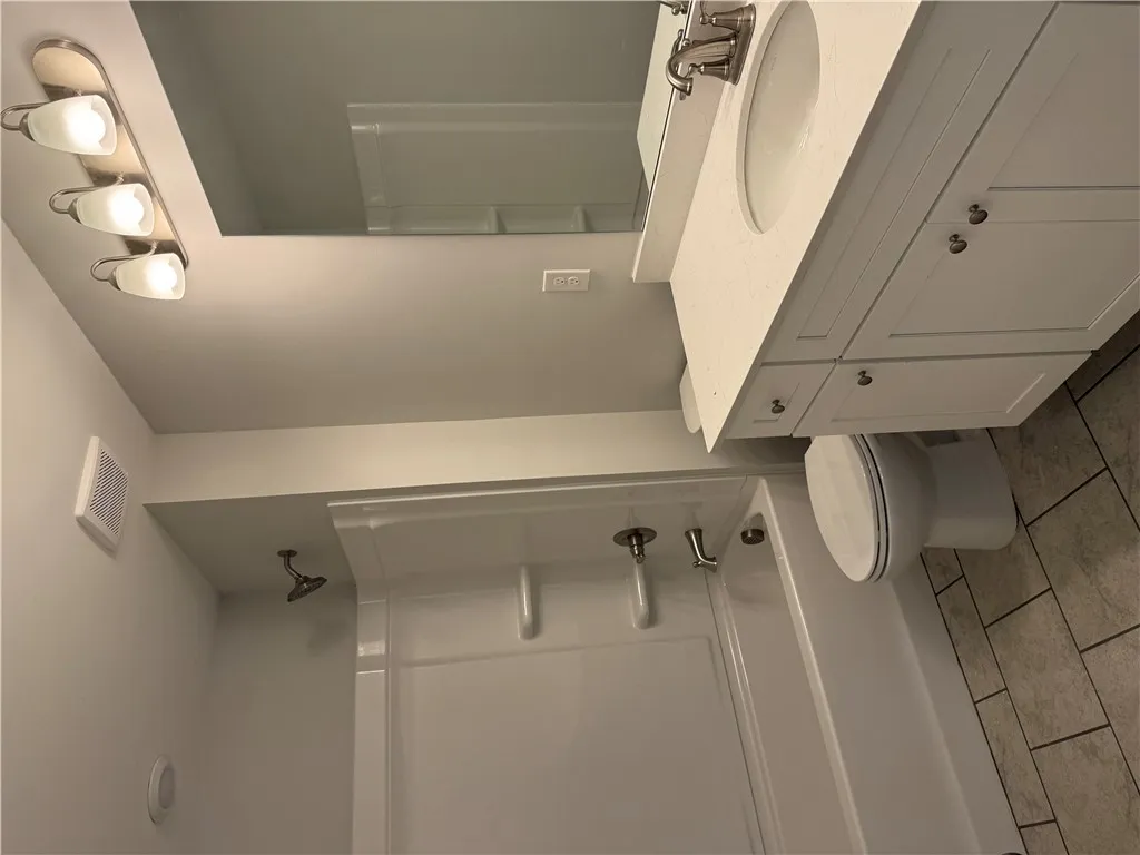 A well-appointed bathroom with contemporary vanity, bright lighting, and a practical shower-tub combination.