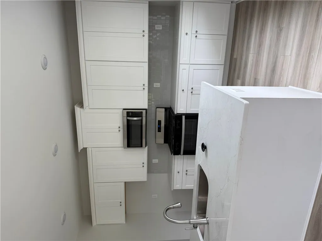 A well-appointed kitchen showcasing white cabinetry, stainless steel appliances, and sleek countertops.