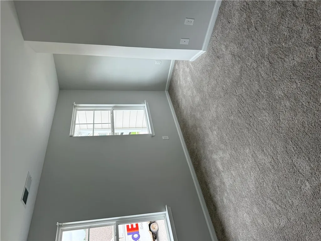 Well-lit living space with soft carpeting and clean, tall walls awaits your personal touch.