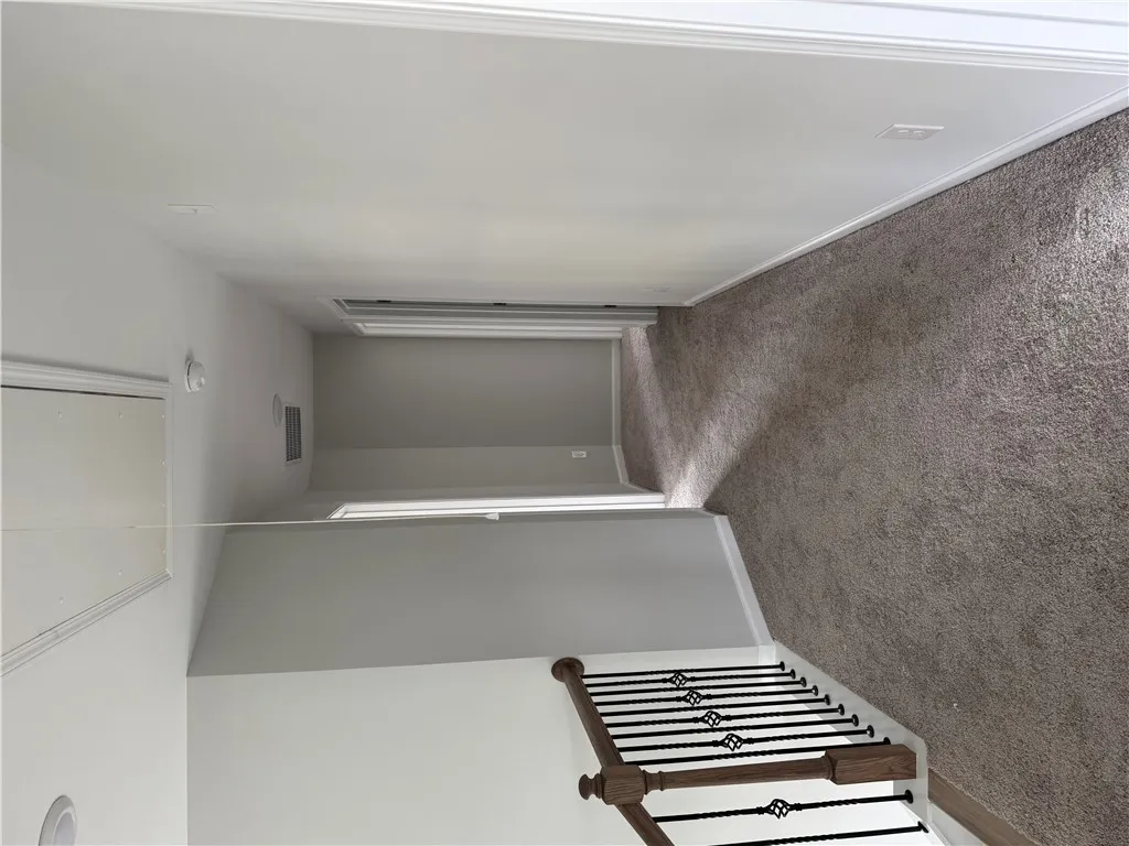 A well-maintained hallway with plush carpet and elegant stair railing awaits.