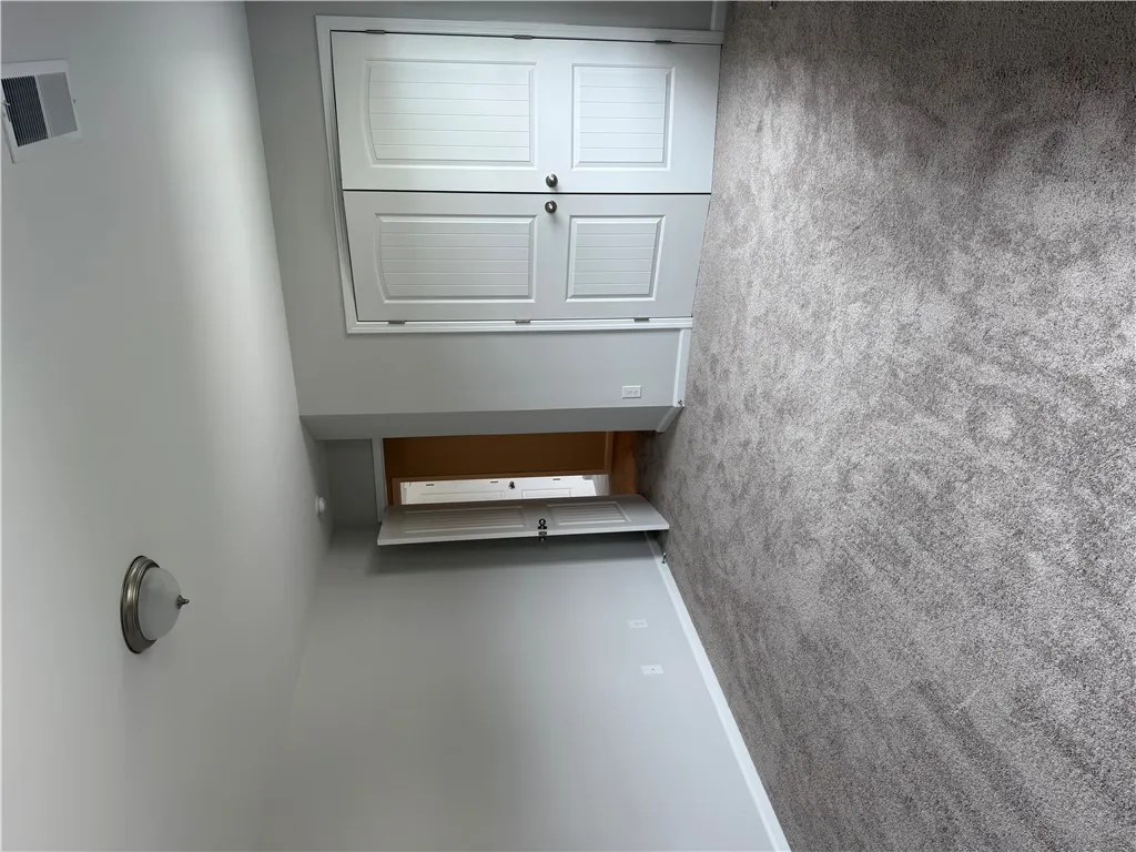 Well-lit room featuring built-in cabinetry and soft, gray carpeting for comfortable living.