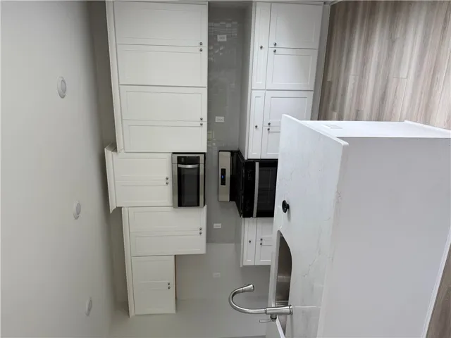 A well-appointed kitchen showcasing white cabinetry, stainless steel appliances, and sleek countertops.