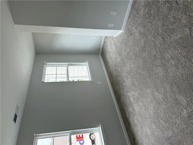 Well-lit living space with soft carpeting and clean, tall walls awaits your personal touch.