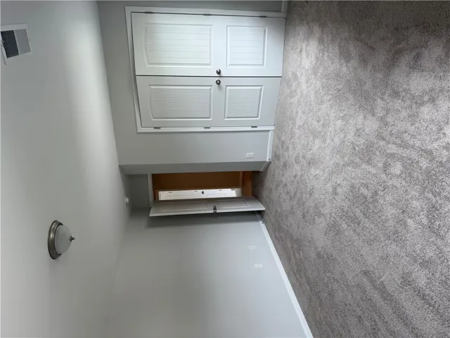 Well-lit room featuring built-in cabinetry and soft, gray carpeting for comfortable living.