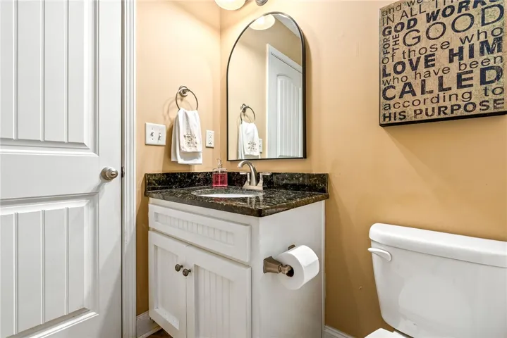 This powder room features a sophisticated granite-topped vanity and an arched mirror, creating a refined atmosphere.