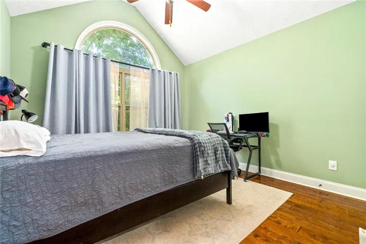 This airy bedroom features high ceilings, rich hardwood floors, and abundant natural light.