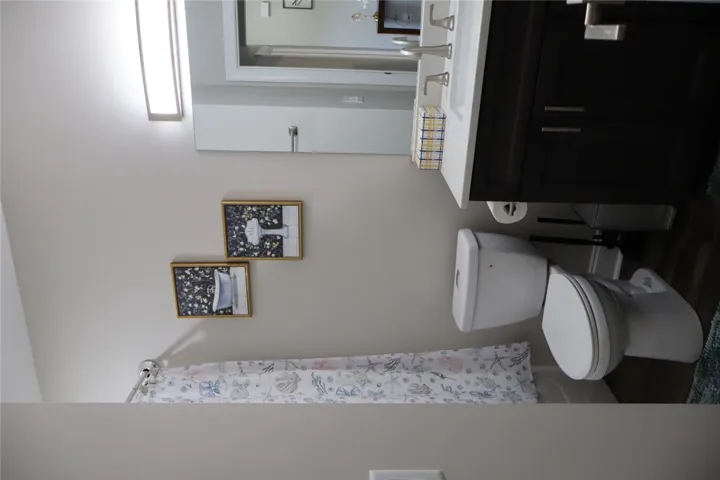This bathroom features elegant dark wood cabinetry paired with a pristine white countertop and a sleek, modern vanity.